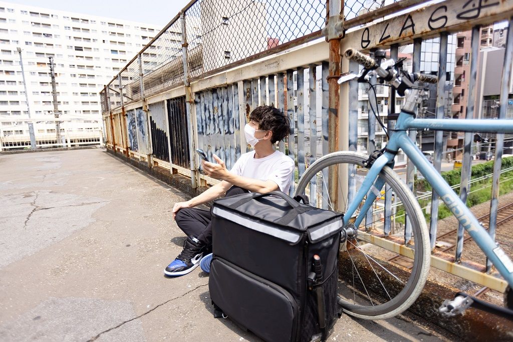 スマートフォンを見ながら休憩する配達員